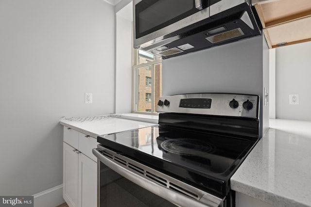 kitchen featuring appliances with stainless steel finishes, light stone counters, and white cabinets