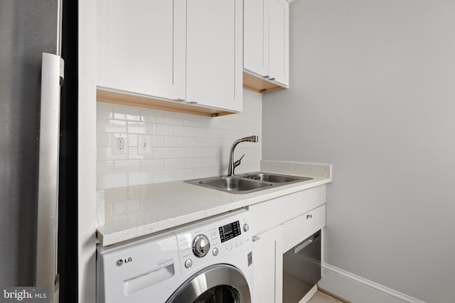 washroom with cabinet space, baseboards, washer / clothes dryer, and a sink