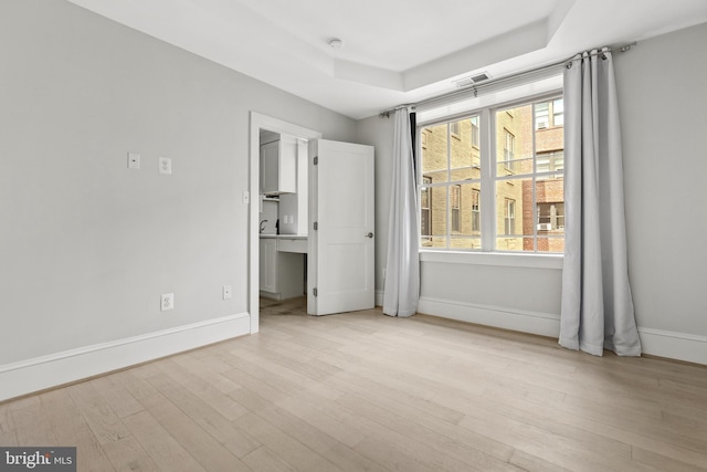 unfurnished bedroom featuring multiple windows, wood finished floors, visible vents, and baseboards