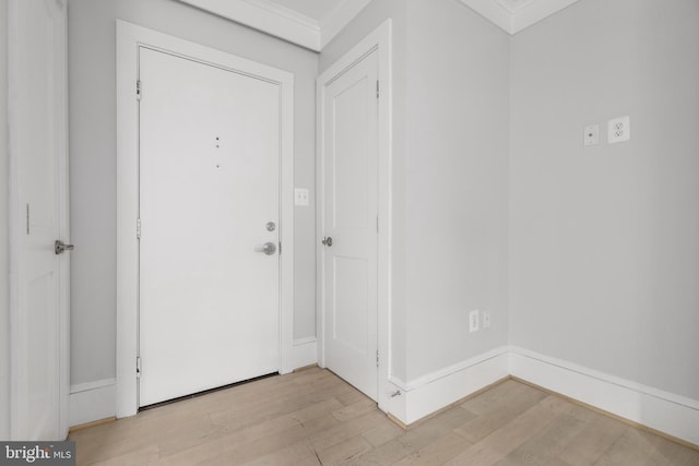 foyer entrance featuring ornamental molding, light wood-type flooring, and baseboards