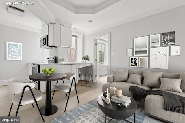 living room with light wood finished floors, visible vents, baseboards, and a raised ceiling