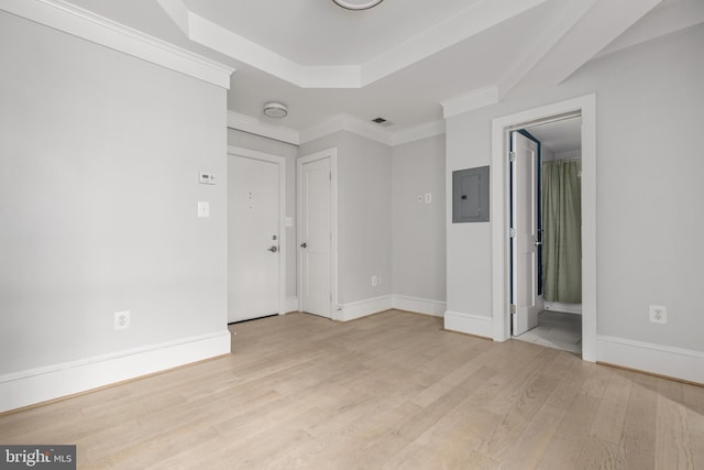 unfurnished room featuring light wood finished floors, electric panel, baseboards, ornamental molding, and a tray ceiling