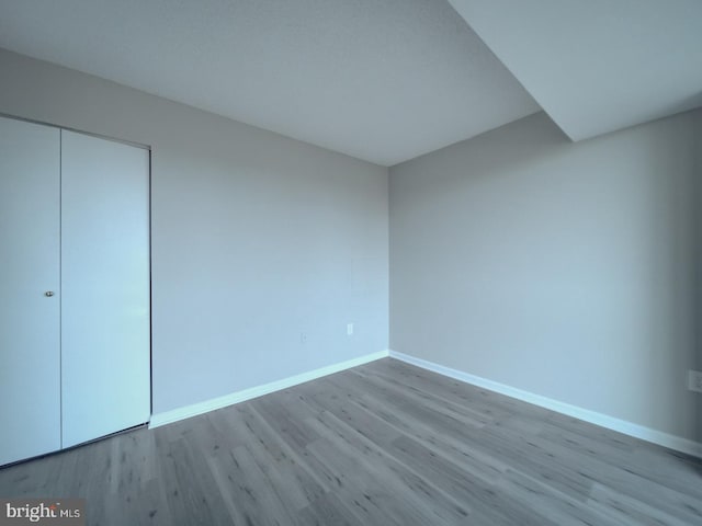 unfurnished bedroom featuring a closet, baseboards, and wood finished floors