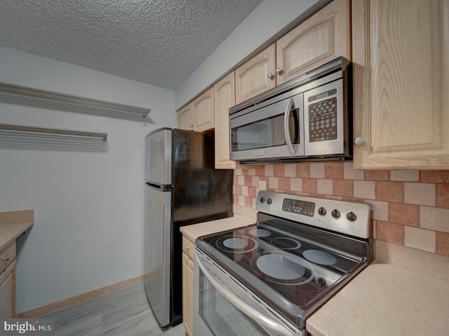 kitchen with tasteful backsplash, light brown cabinets, stainless steel appliances, and light countertops