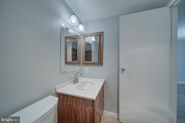 bathroom featuring baseboards, vanity, and toilet