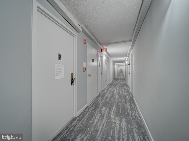 hall featuring baseboards and a textured ceiling