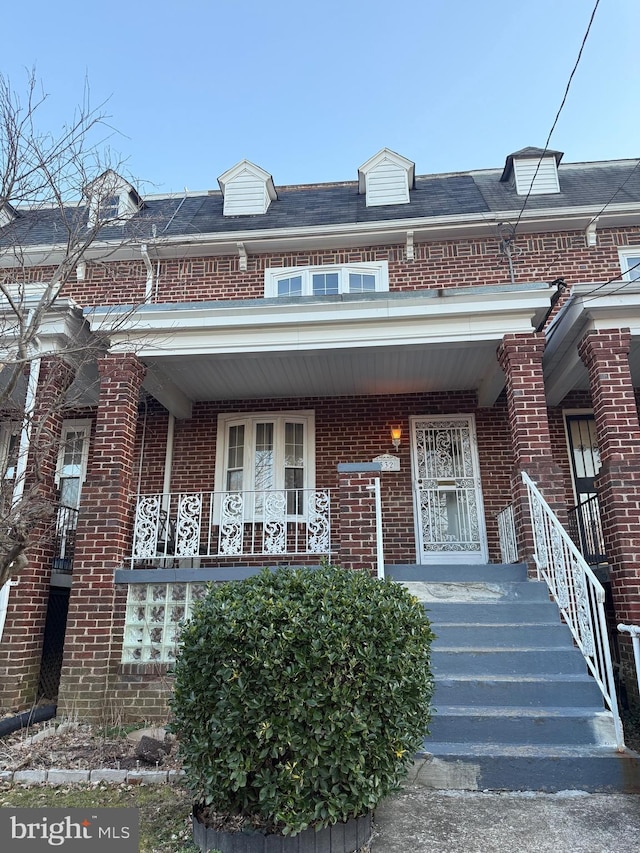 view of property featuring a porch and brick siding