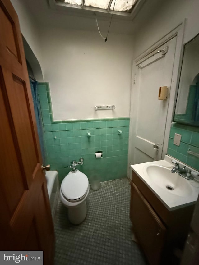 332 Emerson St NW, Washington, DC 20011 - bathroom featuring toilet, a wainscoted wall, tile walls, vanity, and tile patterned floors