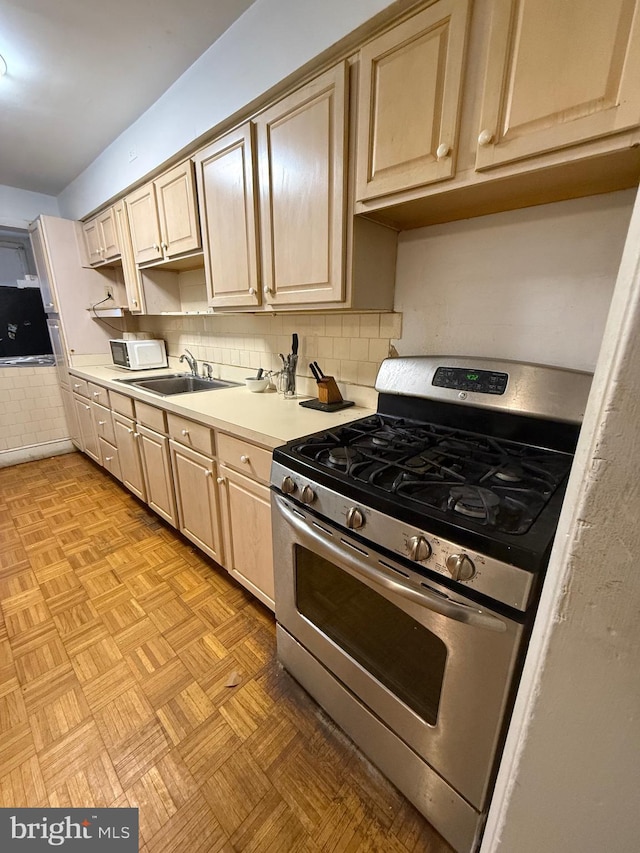 332 Emerson St NW, Washington, DC 20011 - kitchen with tasteful backsplash, light countertops, stainless steel range with gas stovetop, a sink, and light brown cabinets