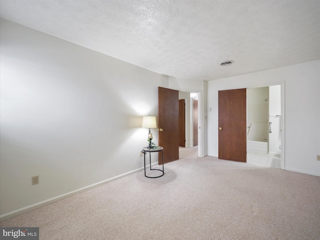 carpeted spare room with visible vents, baseboards, and a textured ceiling