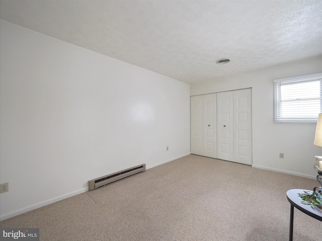 unfurnished room featuring visible vents, baseboards, carpet floors, a textured ceiling, and a baseboard radiator