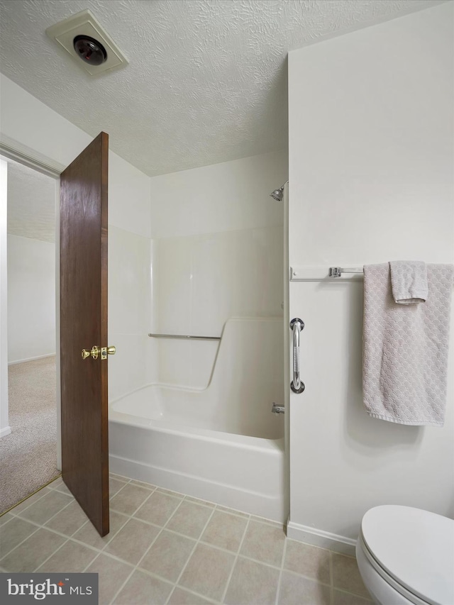 full bathroom featuring tile patterned floors, a textured ceiling, toilet, and shower / tub combination