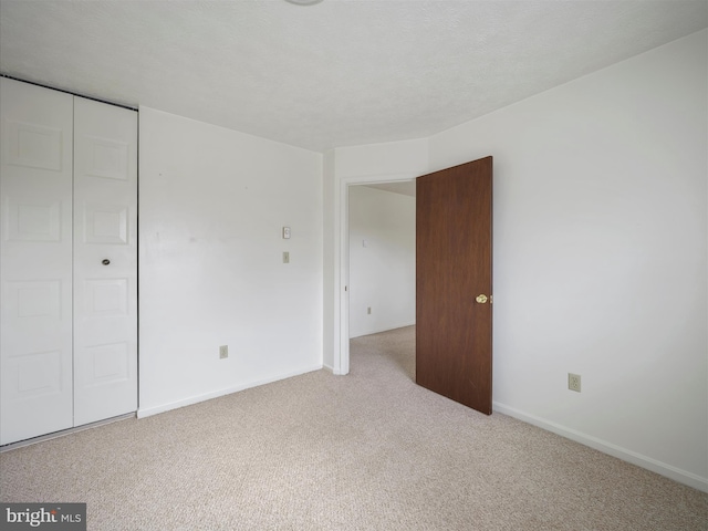 unfurnished bedroom featuring baseboards, carpet floors, a textured ceiling, and a closet