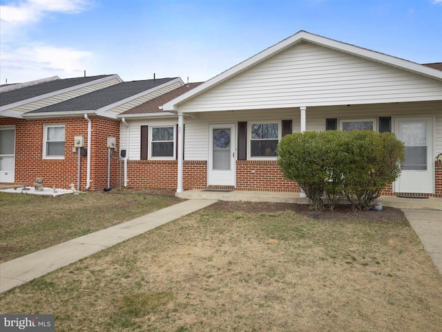 view of front facade with a front yard, brick siding, and a shingled roof