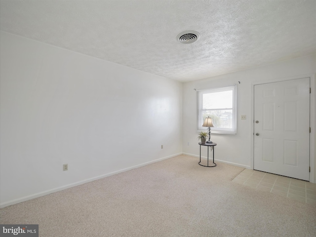 foyer entrance featuring baseboards, carpet, visible vents, and a textured ceiling