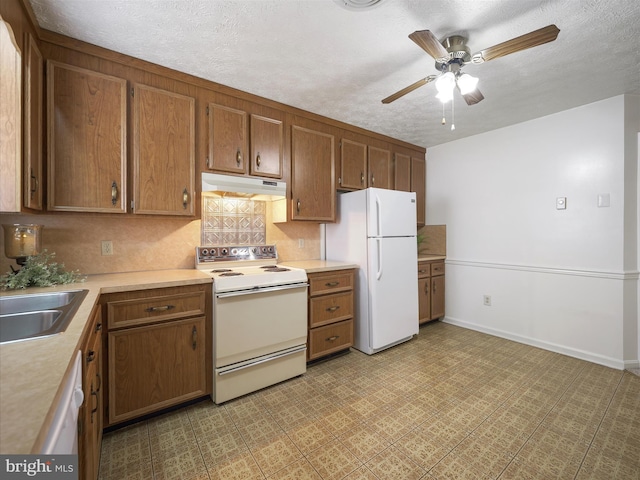 kitchen with white appliances, a ceiling fan, light countertops, under cabinet range hood, and brown cabinets