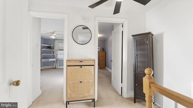 hall featuring baseboards and light colored carpet