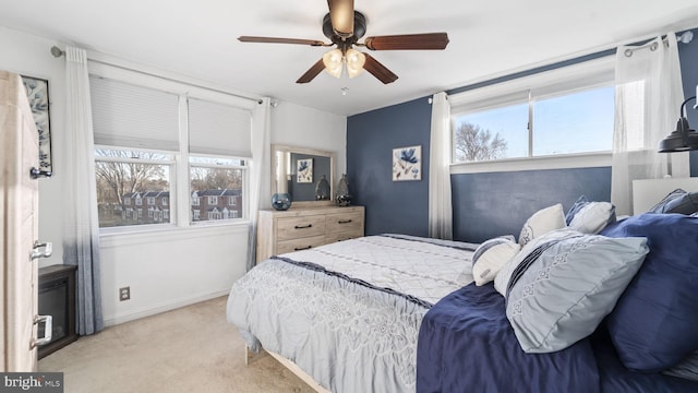 bedroom featuring a ceiling fan, light carpet, baseboards, and multiple windows