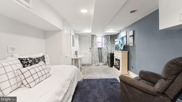 bedroom featuring a lit fireplace and baseboards