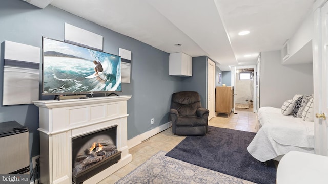 living room with a glass covered fireplace, baseboards, and light tile patterned floors