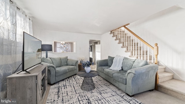 living area with light carpet and stairway