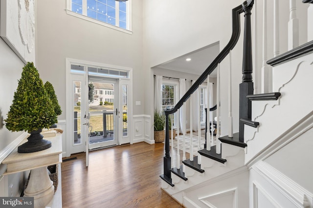 entrance foyer featuring crown molding, a wainscoted wall, stairs, wood finished floors, and a decorative wall