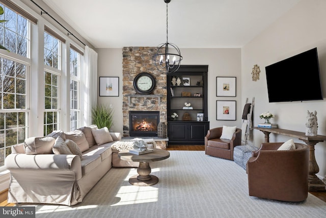 living room featuring a chandelier, a fireplace, and wood finished floors