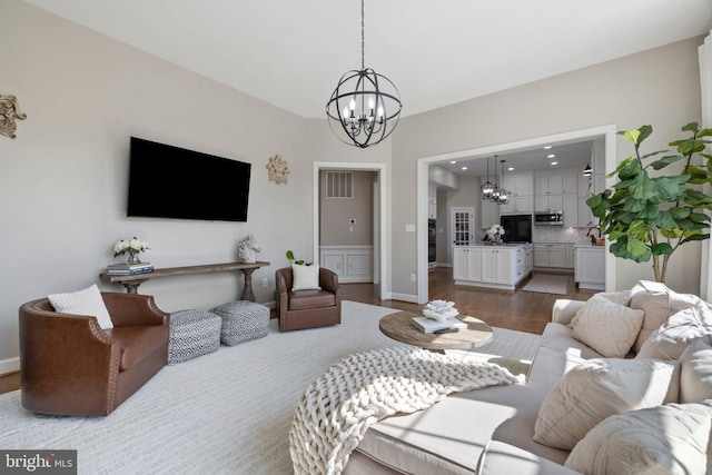 living area with visible vents, baseboards, dark wood-type flooring, and an inviting chandelier