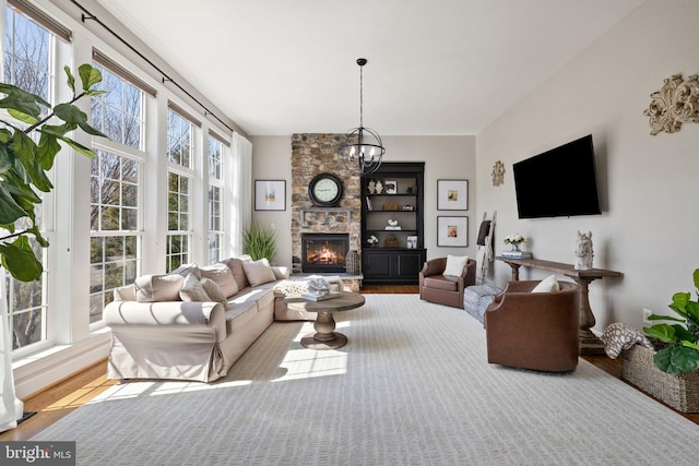 living area with a fireplace, an inviting chandelier, and wood finished floors