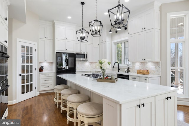 kitchen featuring dark wood finished floors, black appliances, white cabinets, and decorative backsplash