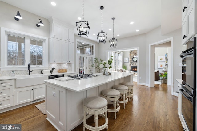 kitchen featuring a kitchen bar, a sink, tasteful backsplash, a center island, and white cabinetry