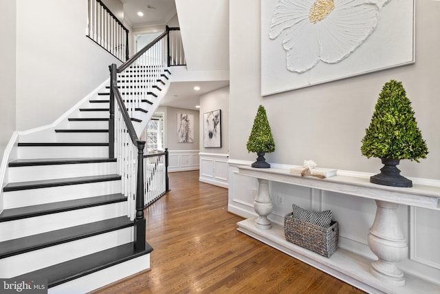 entrance foyer featuring wood finished floors, recessed lighting, wainscoting, a decorative wall, and stairs