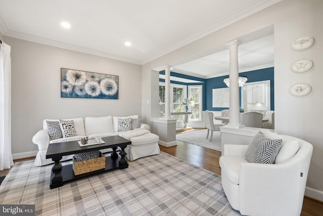 living room with decorative columns, baseboards, wood finished floors, and crown molding