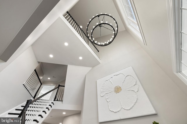 stairway with recessed lighting, a notable chandelier, a high ceiling, and ornamental molding