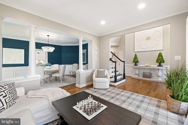 living room featuring wood finished floors, stairs, and decorative columns