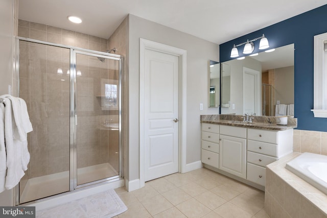 bathroom featuring a garden tub, a shower stall, tile patterned flooring, baseboards, and vanity