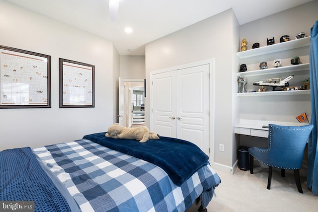 bedroom featuring a ceiling fan, baseboards, built in study area, a closet, and light colored carpet