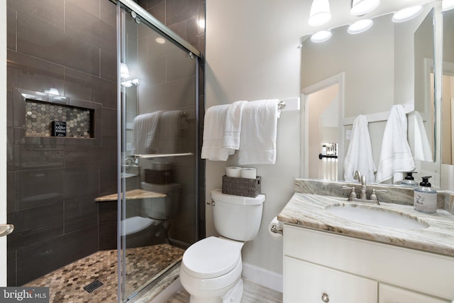 full bathroom with baseboards, vanity, toilet, and a shower stall