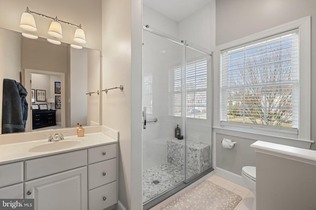 bathroom with toilet, a shower stall, tile patterned flooring, baseboards, and vanity