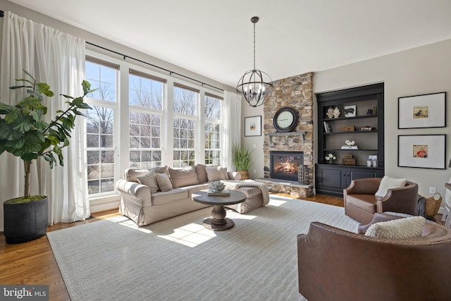 living area with an inviting chandelier, wood finished floors, and a fireplace