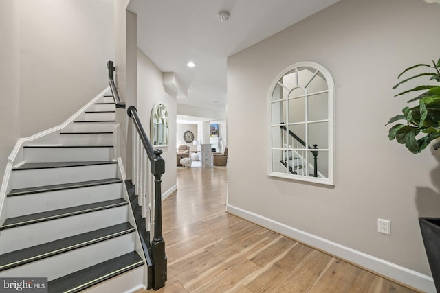 stairs with recessed lighting, wood finished floors, and baseboards