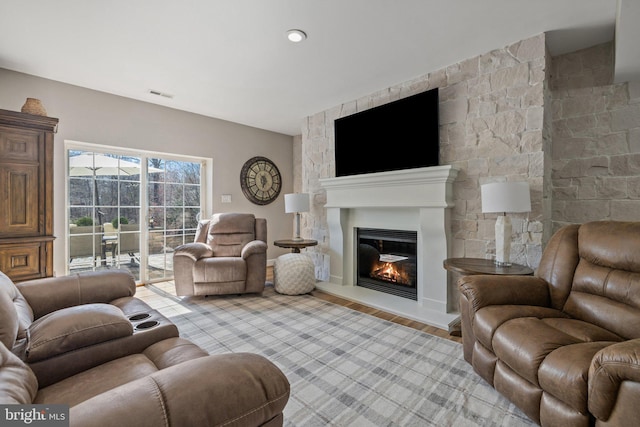 living room featuring visible vents, a large fireplace, and wood finished floors