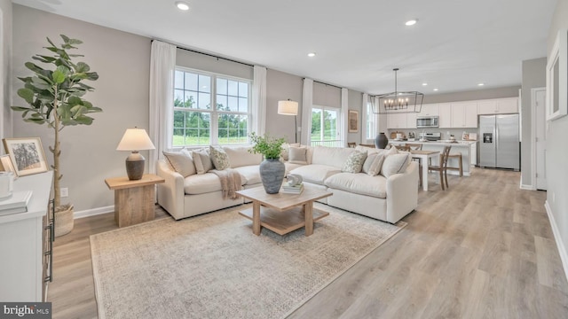 living area featuring light wood-style flooring, baseboards, a chandelier, and recessed lighting