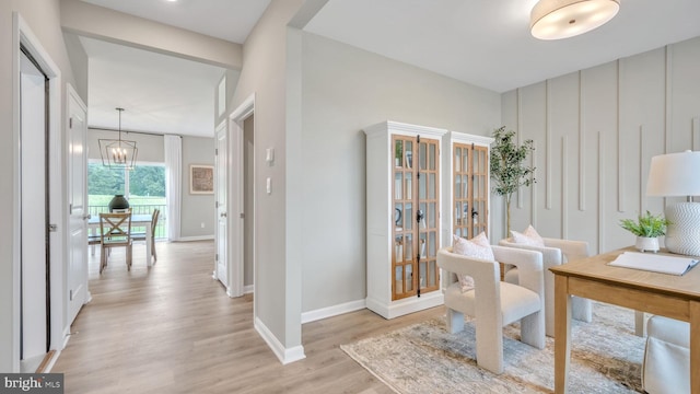 home office with a notable chandelier, light wood-style flooring, and baseboards