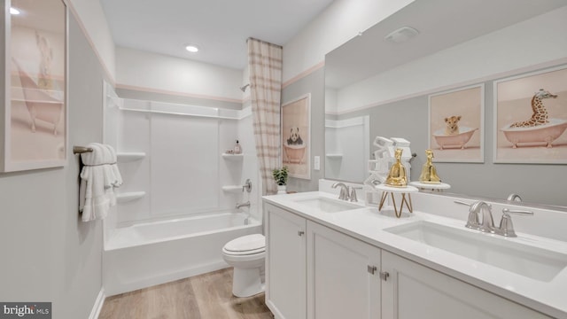 bathroom with double vanity, wood finished floors, a sink, and toilet