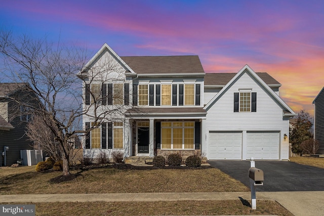 traditional-style home featuring a garage, aphalt driveway, and roof with shingles