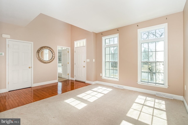 foyer entrance with carpet floors, visible vents, and baseboards