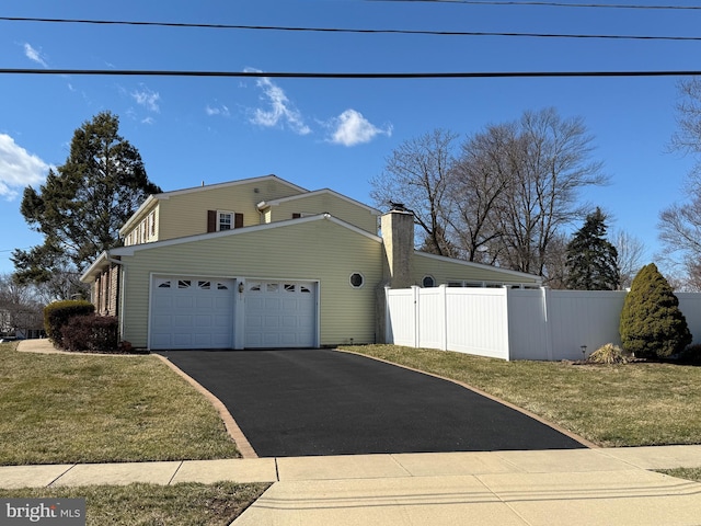 view of property exterior featuring driveway, a yard, an attached garage, and fence