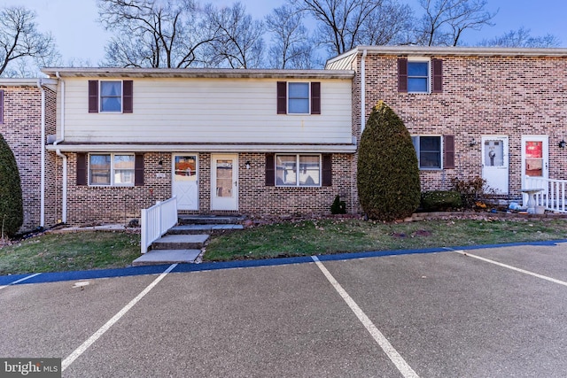 view of property featuring uncovered parking and brick siding