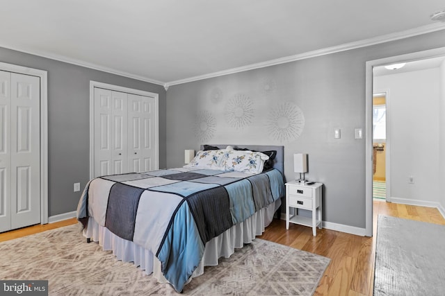 bedroom with baseboards, crown molding, multiple closets, and wood finished floors